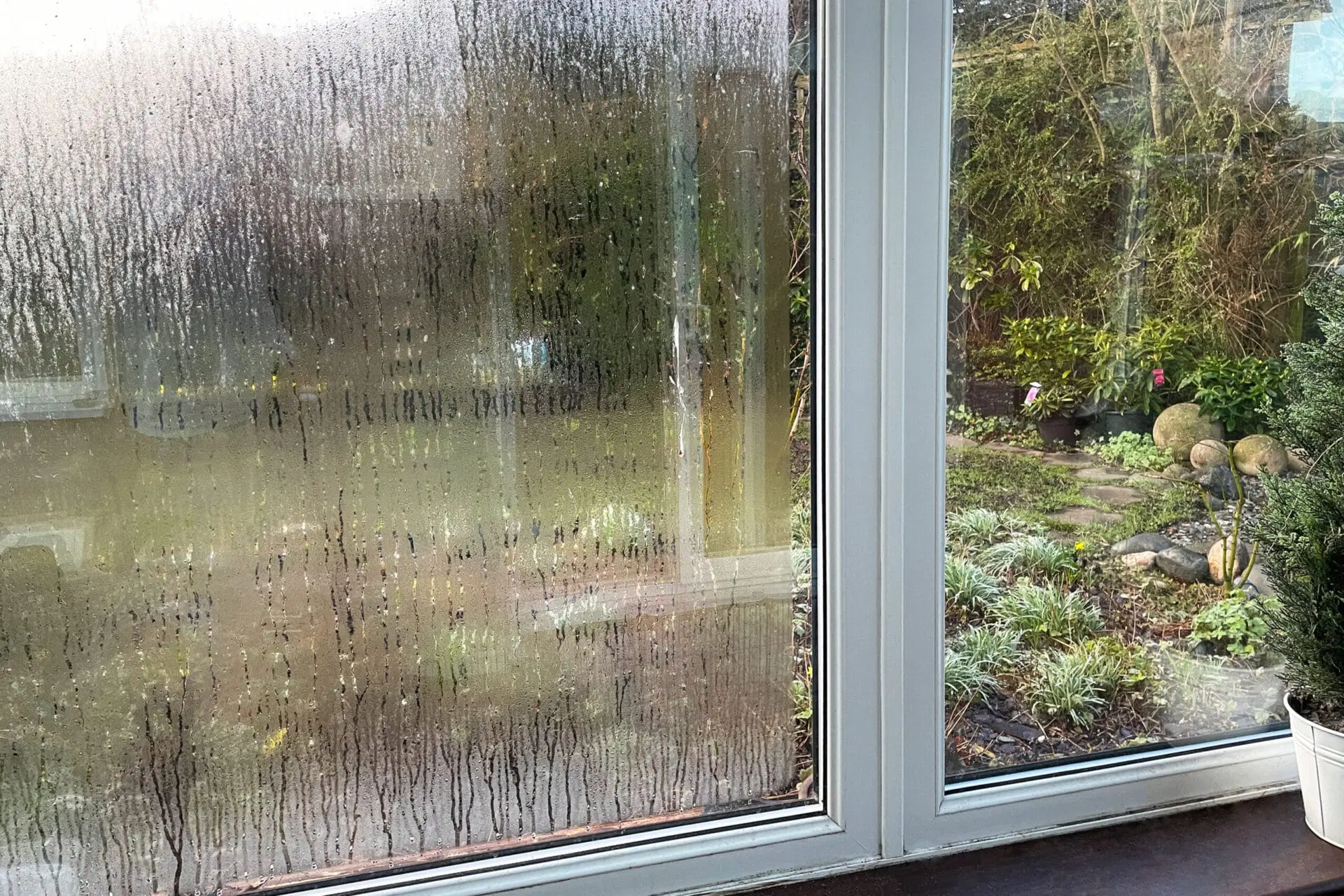 A dirty, fogged-up window with streaks and water droplets is shown next to a clean, clear window, creating a striking contrast